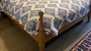 Ein Schlafzimmer mit einem hölzernen Bett, einem Nachttisch, einer Lampe, einem Schrank und einem gerahmten Bild an der Wand.