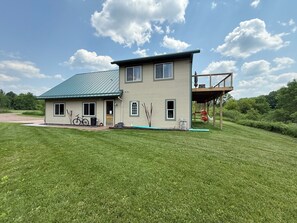 A two-story house with a green roof, a balcony, and a well-maintained lawn. - The Eagle’s Nest perched above the Jump River! (Sheldon)