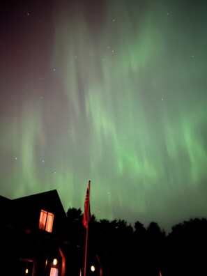 Una casa con asta de bandera y vistas de las auroras boreales.