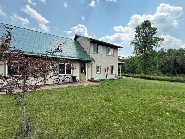 A two-story house with a green roof, a front porch, and a well-maintained lawn. - The Eagle’s Nest perched above the Jump River! (Sheldon)