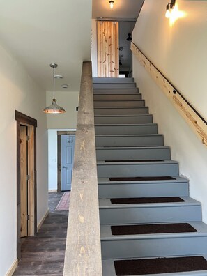 Una escalera con barandilla de madera y pared de color claro.