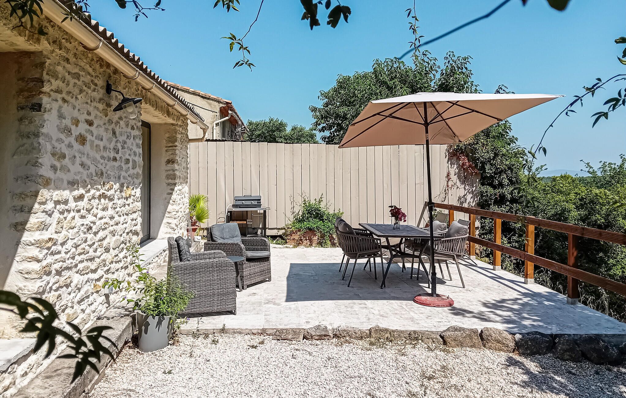 A patio with outdoor furniture, a grill, and a wooden fence.