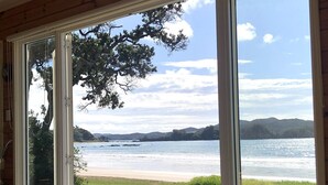 Ein Zimmer mit einer großen Schiebeglastür und Blick auf einen Strand.