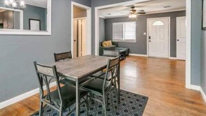 A dining area with a wooden table and chairs, a chandelier, and a patterned rug. - Oasis in Central Oklahoma City (Oklahoma City)