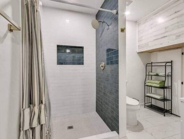 Een douche, handdoeken, zeep, toiletpapier