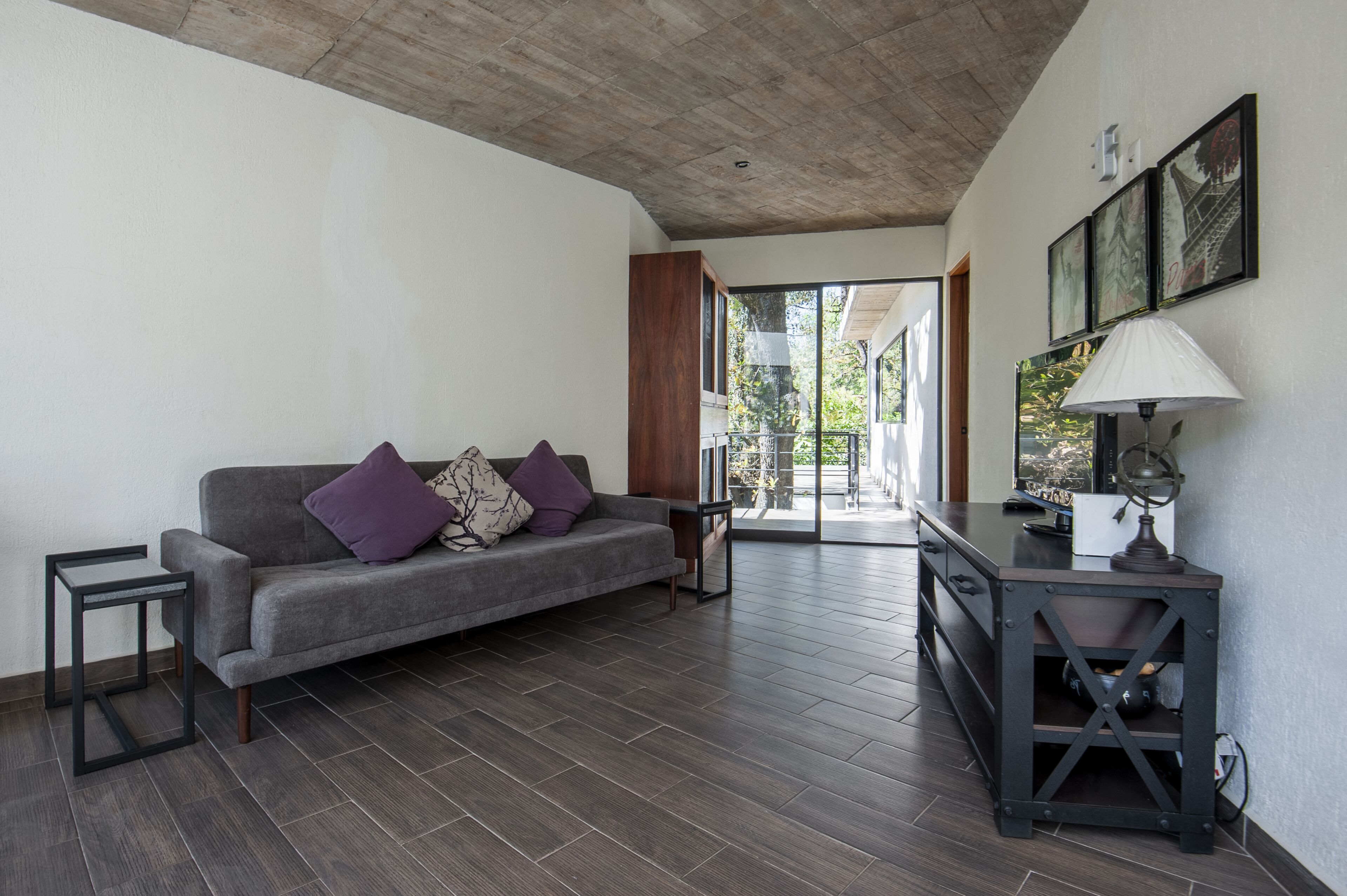 Un salon moderne avec un canapé gris, une petite table et un bureau en bois foncé.