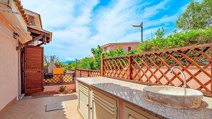 A rooftop terrace with a stone sink, a wooden door, and a lattice fence.