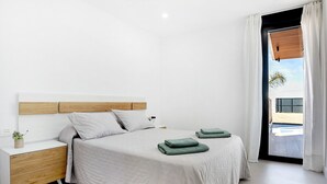 A modern bedroom with a bed, nightstand, and a view of the outside. - Holiday Home 'Casa Adriana' with Private Pool, Wi-Fi and Air Conditioning (Conil de la frontera)