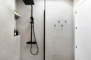 A modern shower with a handheld showerhead and a wall-mounted control panel.