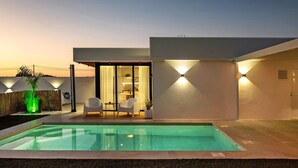 A modern house with a swimming pool, two white chairs, and a glass door leading to an interior space. - Holiday Home 'Casa Adriana' with Private Pool, Wi-Fi and Air Conditioning (Conil de la frontera)