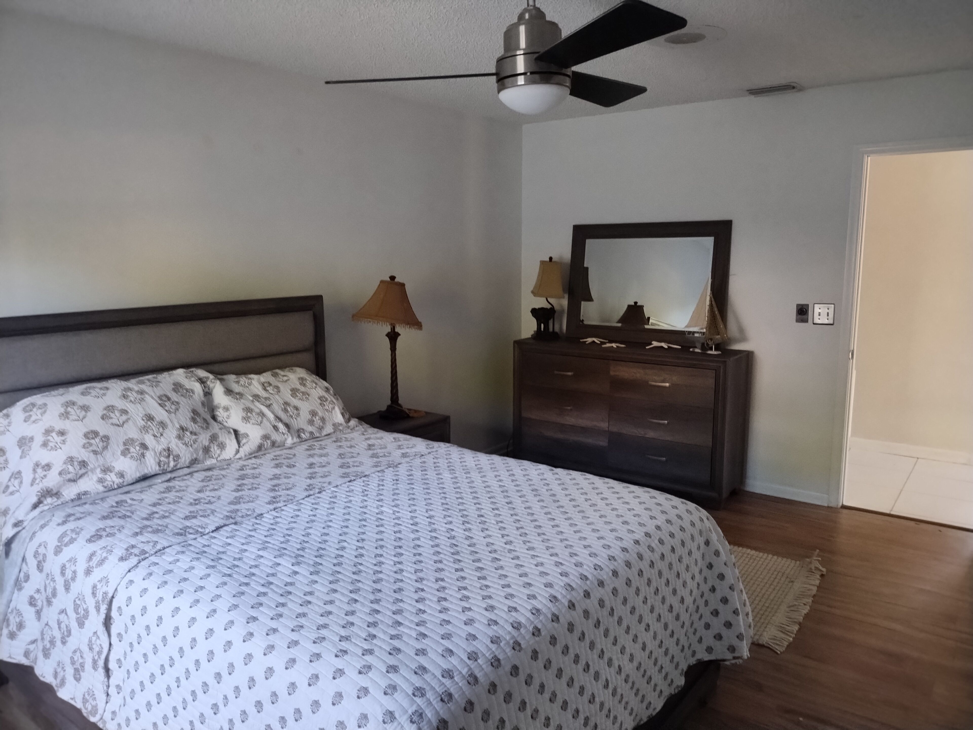 Ein Schlafzimmer mit Bett, Kommode und Deckenventilator.