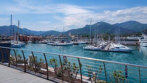 Un port de plaisance avec des bateaux amarrés, un ciel dégagé et des montagnes en arrière-plan.