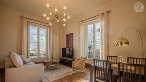 A living room with a sofa, a TV, a dining table with chairs, and a chandelier. - LE Pinot - Porte-de-savoie (PORTE-DE-SAVOIE)