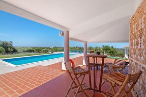 Un'area esterna coperta con piscina, lettini e un tavolo con bevande.