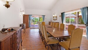 Un espace repas comprenant une longue table en bois, des chaises et un buffet garni de plats.