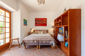 Une chambre à coucher avec un lit, un banc en bois, une bibliothèque et une fenêtre.