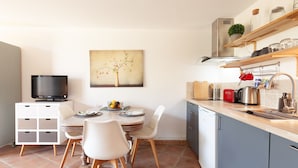 Eine moderne Küche mit Essbereich, einem Fernseher und einem Bild an der Wand.