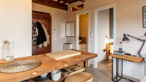 Une cuisine avec une table en bois, une planche à découper, une bouilloire et une lampe.