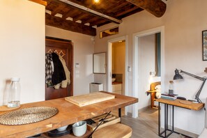 Une cuisine avec une table en bois, une planche à découper, une bouilloire et une lampe.