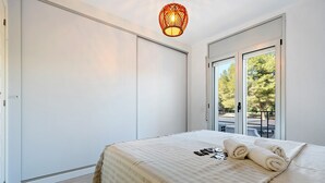 Une chambre à coucher avec un lit, une grande fenêtre et une porte.