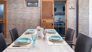 A dining area with a brick wall, wooden doors, and a table set with plates, glasses, and cutlery.