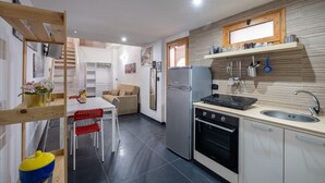 A modern kitchen with a refrigerator, oven, and sink. There is a dining area with a table and chairs.