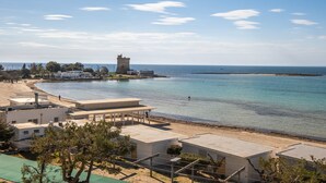 A coastal hotel with a beach view, a tower, and a clear sky.