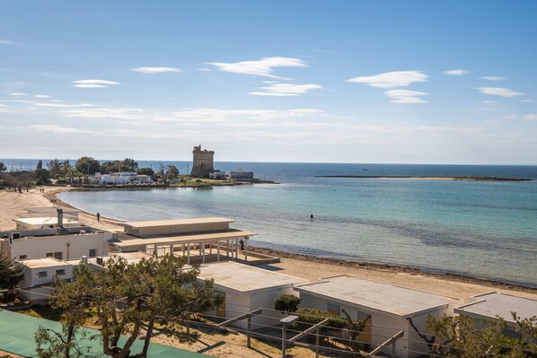 A coastal hotel with a beach view, a tower, and a clear sky.