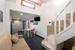 Een modern interieur met een bank, eettafel, stoelen, een televisie en een trap.