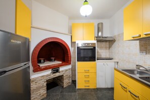 Una cocina con horno empotrado, estufa, horno de ladrillo rojo y armarios amarillos.