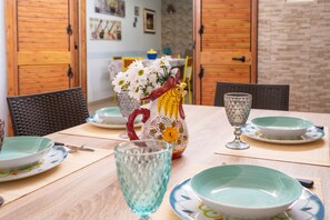 A dining table with plates, glasses, and a vase with flowers. - Holiday Home 'Villa Gaudì - Batllò' with Private Terrace, Wi-Fi and Air Conditioning (Sant'Isidoro)
