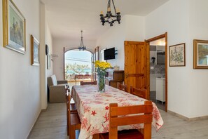 Een eethoek met een tafel gedekt voor vier personen, een vaas met gele bloemen en een kroonluchter.
