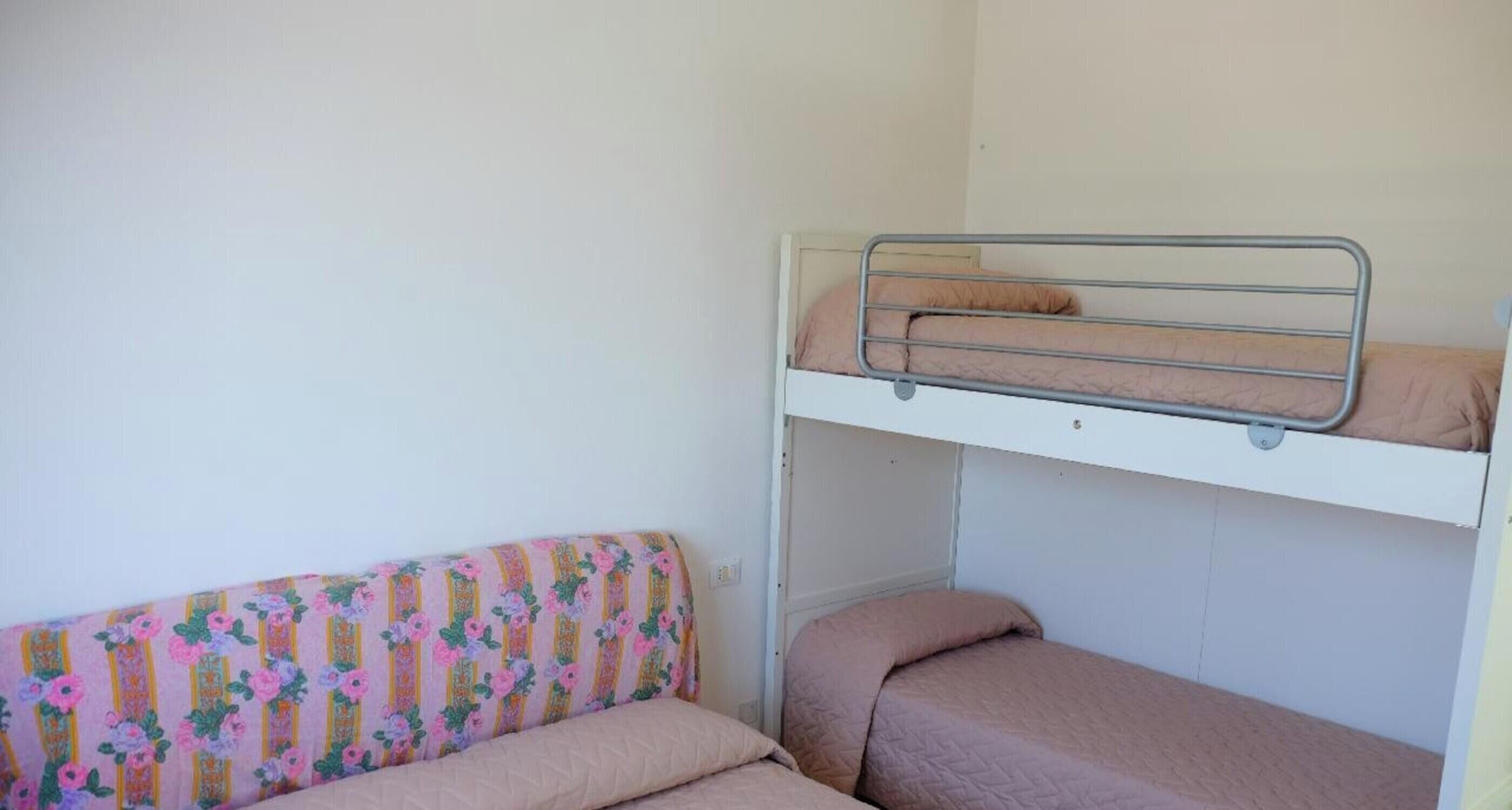 Un lit superposé avec un lit en bas et un matelas posé sur le sol.