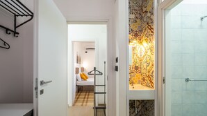 A hallway leading to a bedroom with a bed, a hanging rack, and a bathroom with patterned tiles. - Holiday Home 'Villa Gaudì - Milà' with Private Terrace, Wi-Fi and Air Conditioning (Sant'Isidoro)