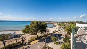 A coastal road with a beach, trees, and a building with solar panels. - Holiday Home 'Villa Gaudì - Milà' with Private Terrace, Wi-Fi and Air Conditioning (Sant'Isidoro)