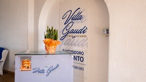 A reception desk with a sign reading 'Villa Gaudi' and a small model building. - Holiday Home 'Villa Gaudì - Milà' with Private Terrace, Wi-Fi and Air Conditioning (Sant'Isidoro)