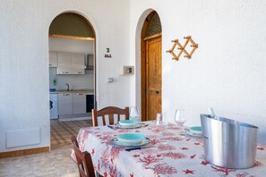 A dining area with a table set for two, a kitchen in the background, and a wooden door with a number '3' above it.