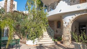 A courtyard with a staircase, a bench, potted plants, and a stone wall. - Holiday Home 'Villa Gaudì - Milà' with Private Terrace, Wi-Fi and Air Conditioning (Sant'Isidoro)