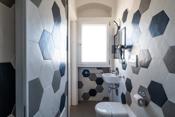A bathroom with a hexagonal tile pattern, a toilet, a sink, and a mirror.
