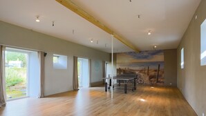 Una habitación amplia con suelo de madera, ventanas grandes y vistas al exterior.