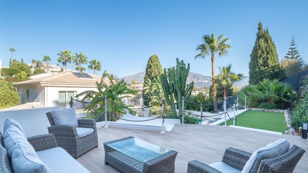 A patio with wicker furniture, a glass-top table, and a view of a mountain. - Villa 'Jazmin' with Mountain View, Wi-Fi and Air Conditioning (Mijas Costa)
