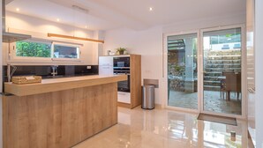 A modern kitchen with a wooden island, built-in appliances, and a sliding glass door leading to an outdoor area. - Villa 'Jazmin' with Mountain View, Wi-Fi and Air Conditioning (Mijas Costa)