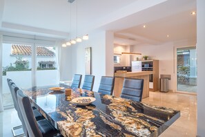Un comedor moderno con una mesa de mármol, sillas negras y una cocina al fondo.