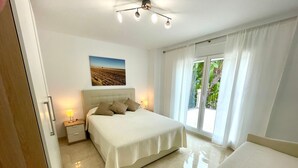 A bedroom with a bed, a nightstand, a lamp, a window with curtains, and a view of greenery outside. - Villa 'Jazmin' with Mountain View, Wi-Fi and Air Conditioning (Mijas Costa)