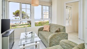 A living room with a sofa, a glass coffee table, and a television. - Apartment 'Primera Línea con Terrace A104' with Sea View, Shared Pool and Wi-Fi (Torrox)