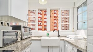 A kitchen with a microwave, toaster, sink, and washing machine. - Apartment 'Primera Línea con Terrace A104' with Sea View, Shared Pool and Wi-Fi (Torrox)