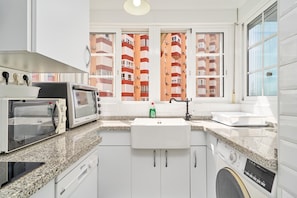 A kitchen with a microwave, toaster, sink, and washing machine. - Apartment 'Primera Línea con Terrace A104' with Sea View, Shared Pool and Wi-Fi (Torrox)