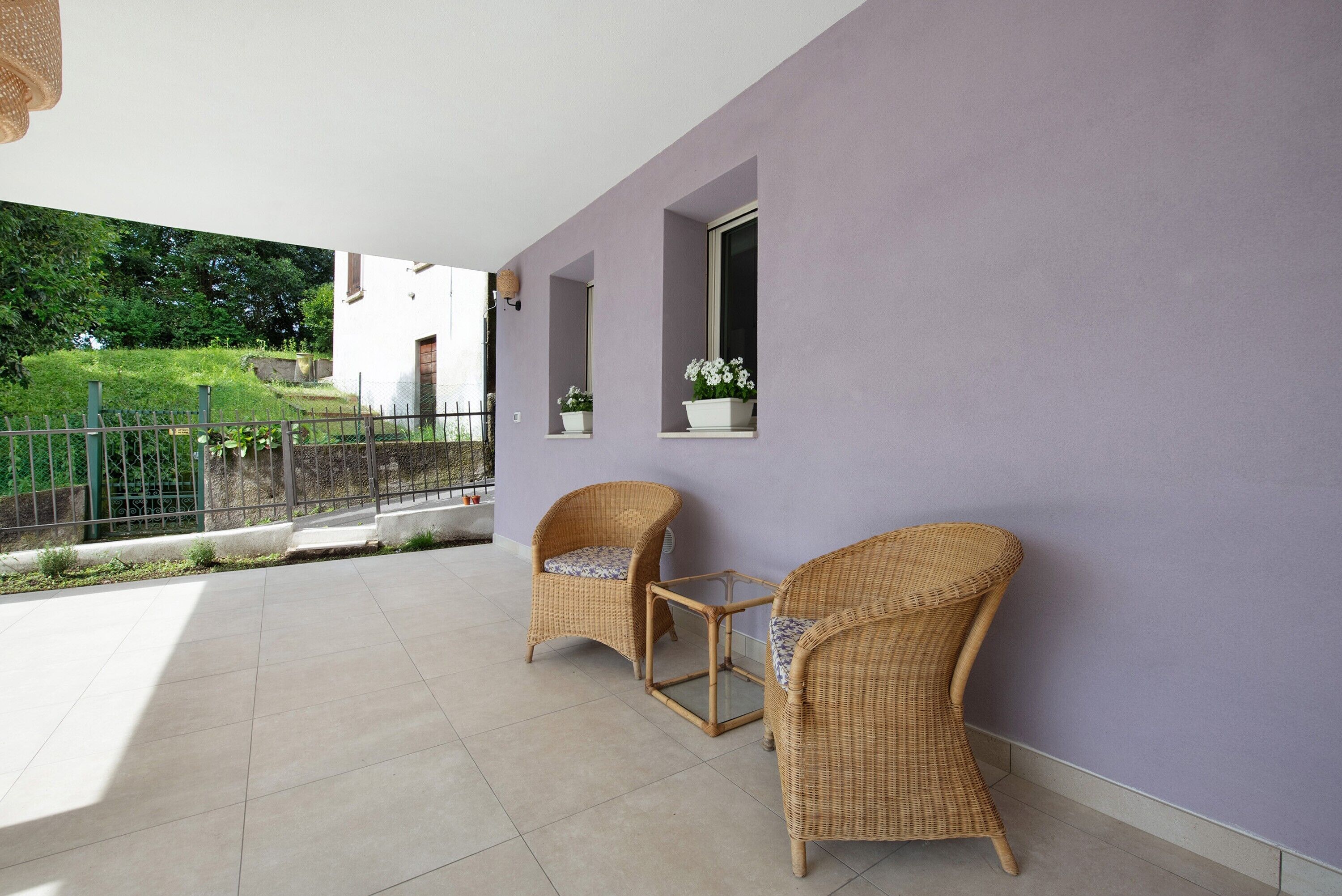 Un balcon avec deux fauteuils en osier, une petite table et un pot de fleurs.