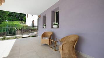 Un balcon avec deux fauteuils en osier, une petite table et un pot de fleurs.