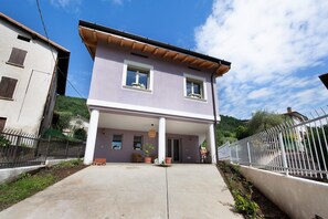 Une maison à deux étages avec un porche, un vélo et une clôture.
